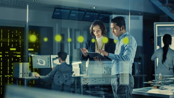 A woman and a man working together on a tablet computer while standing
