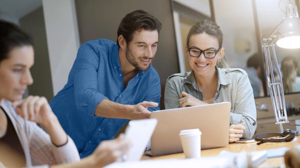 A man shows a woman something on a notebook.